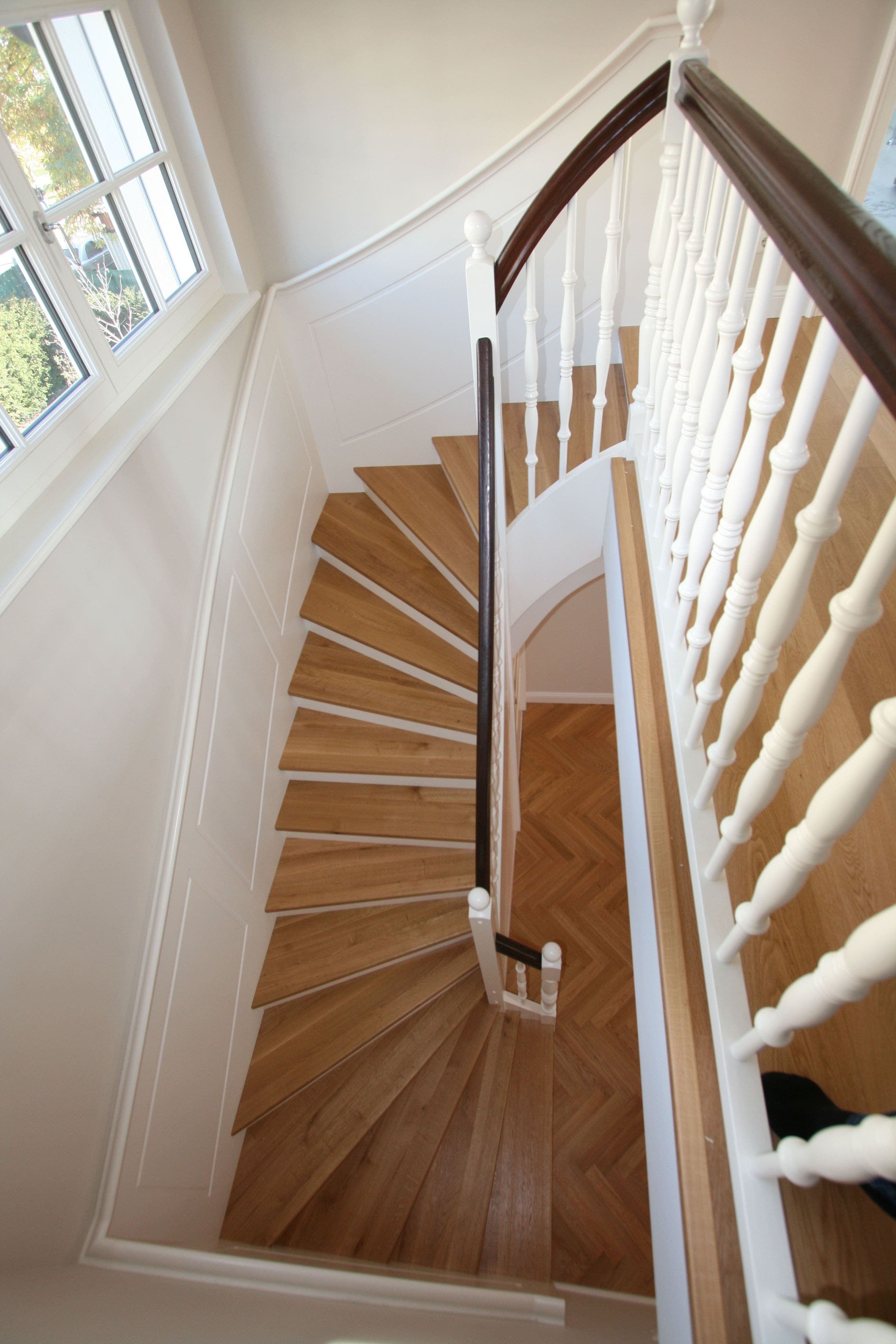 Geschwungene Betonstiege mit Massivholzstufen und klassischem Geländer - Bild 2