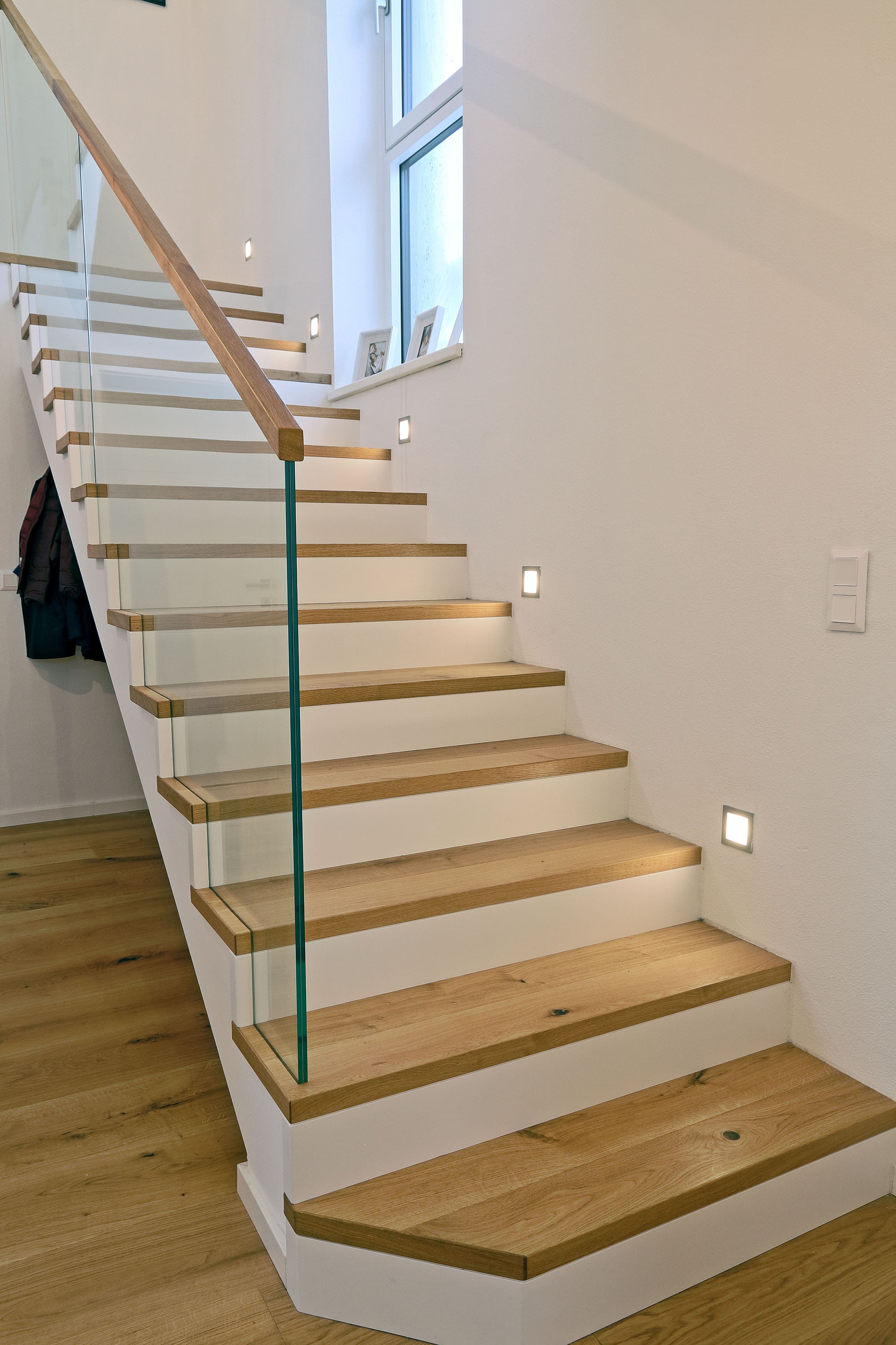 Moderne Holztreppe mit weißen Setzstufen und Glasgeländer - Bild 1