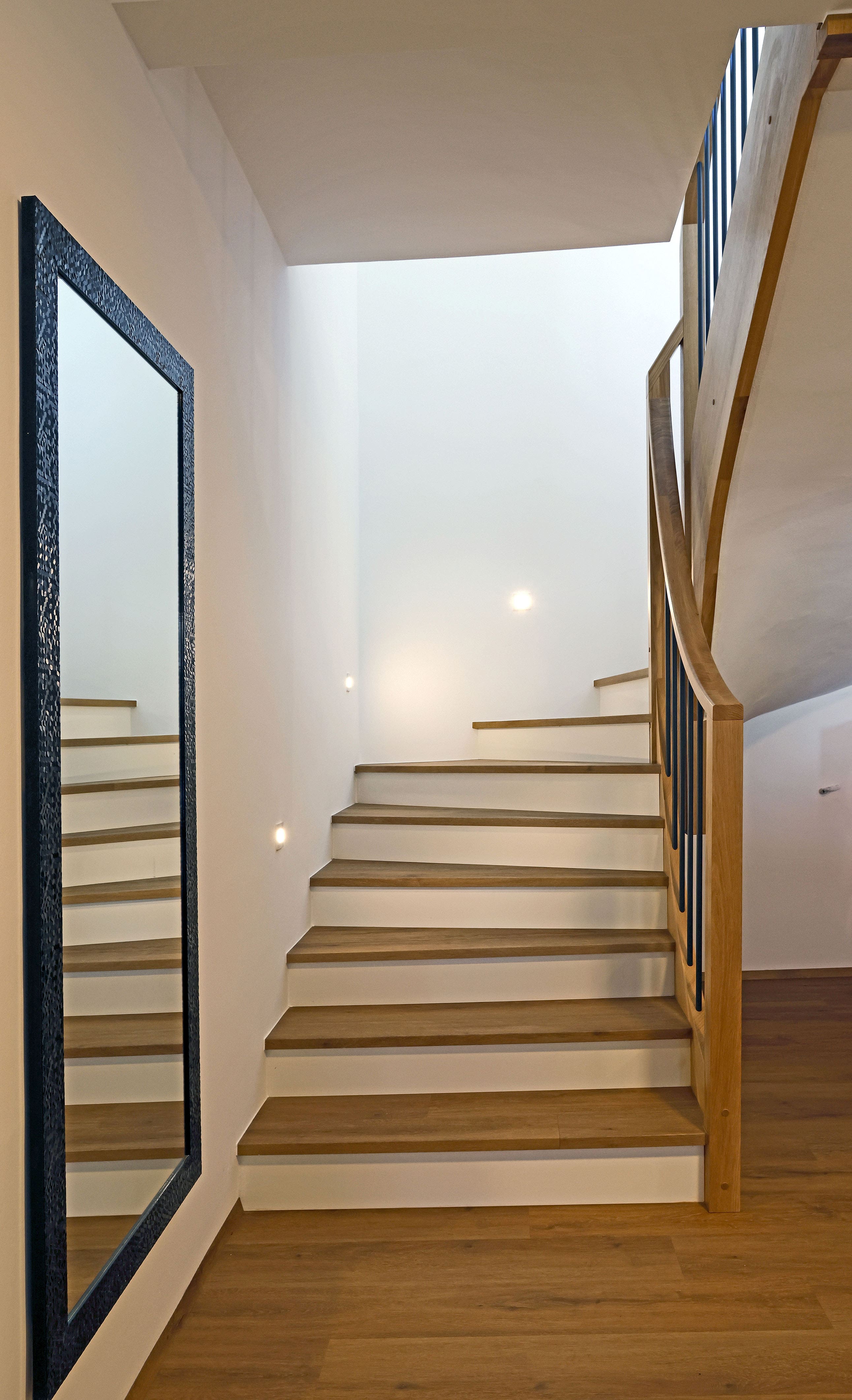 Geschwungene Betonstiege mit Holzauftritten und Holzgeländer